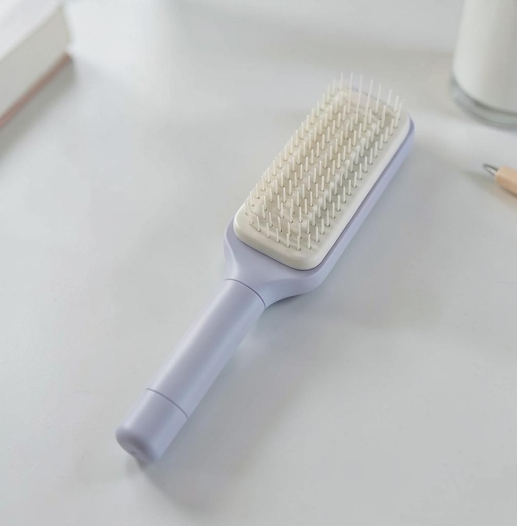 Snaggedly 4-in-1 self-cleaning hair brush in pastel purple with a rectangular head and anti-static bristles.