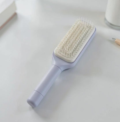 Snaggedly 4-in-1 self-cleaning hair brush in pastel purple with a rectangular head and anti-static bristles.